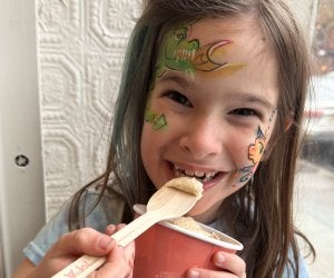 Kid-friendly summer eats in Brooklyn: girl in face paint smiling with spoonful of ice cream